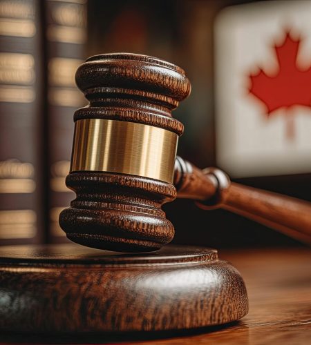 Gavel rests on sound block near law books and Canadian flag Gavel rests on sound block near law books and Canadian flag