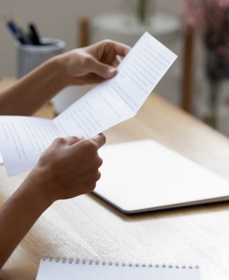 Close up young woman holding paper letter with good news. Close up young woman holding paper letter with good news, getting banking loan approval. Millennial businesswoman received correspondence, reading fashion show or special event invitation indoors.