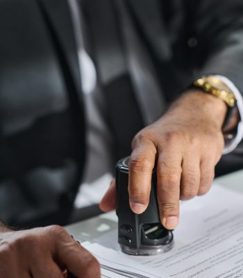 Solicitor putting stamp on contract Hand of mature unrecognizable male lawyer or solicitor putting stamp on contract or other paper document after signing them